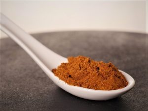 Cuchara con una mezcla de especias de color naranja-marrón llamada adobo carnes