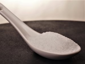 Cuchara llena de Glutamato monosódico. en forma de polvo con un color blanco y una textura y aspecto suave.