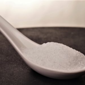 Cuchara llena de Glutamato monosódico. en forma de polvo con un color blanco y una textura y aspecto suave.