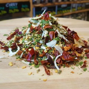 Montoncíto de condimento Arrabbiata: Cayenas secas en rodajas con hierbas aromáticas encima de una tabla de madera