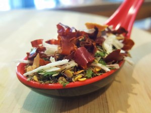 Condimento Arrabbiata: Cayenas secas en rodajas con hierbas aromáticas en una cuchara encima de una tabla de madera