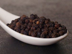 Granos de pimienta negra en una cuchara de porcelana en la tienda de especias Sally Pepper en Madrid