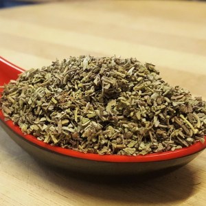 Cuchara de sopa de tipo oriental, de color rojo y negro, llena de salvia triturada en la rienda de especias Sally Pepper en Madrid.