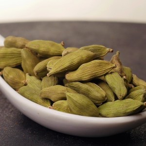 Cuchara de cerámica llena de vainas de cardamomo verde en la tienda de especias Sally Pepper en Madrid