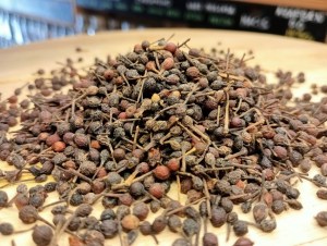 Montón de granos de pimienta voatsiperifery encima de una tabla de madera en la tienda de especias Sally Pepper en Madrid